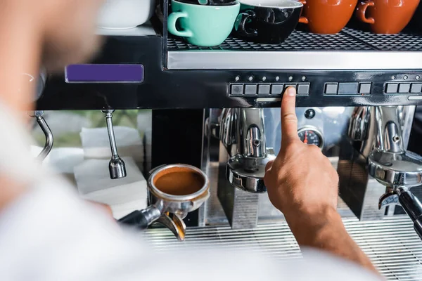 Vista cortada de barista pressionando botão na máquina de café enquanto segurando portafilter, foreground borrado — Fotografia de Stock