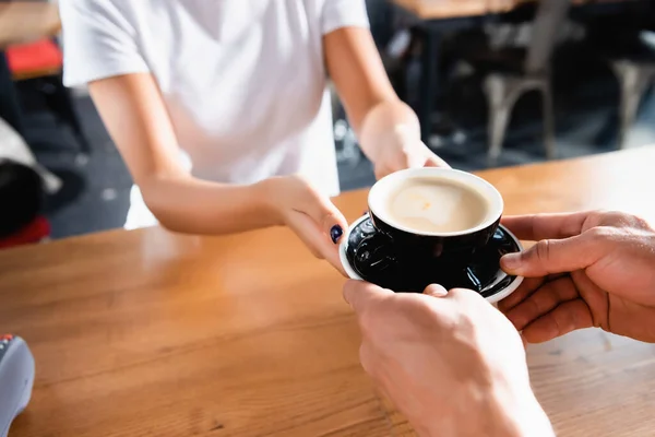 Cropped view of man taking cup of coffee from barista on blurred background — Stock Photo