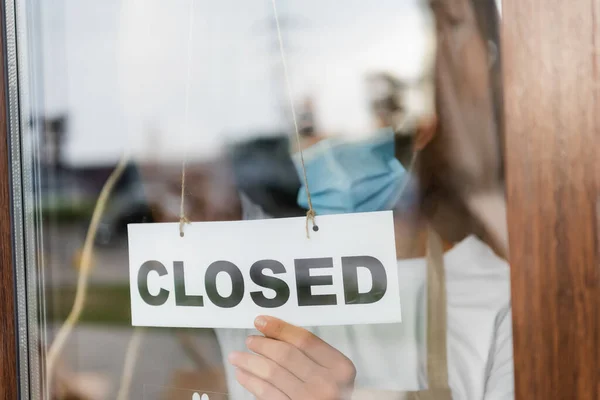 Waiter in medical mask hanging card with closed lettering on cafe entrance door — Stock Photo