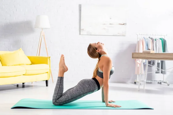 Vue latérale de la jeune femme aux yeux fermés pratiquant le yoga à la maison — Photo de stock