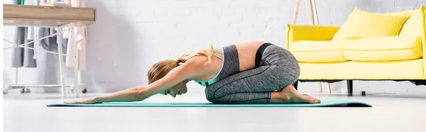 Vue latérale d'une sportive pieds nus faisant du yoga asana sur tapis de fitness, bannière — Photo de stock