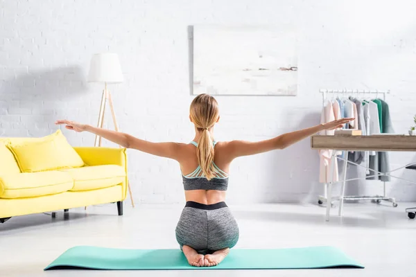 Vista posteriore della donna che pratica yoga sul tappeto fitness sul pavimento a casa — Foto stock