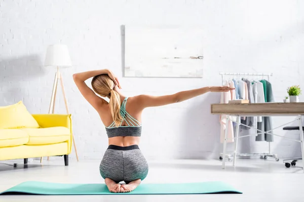 Vista posterior de la mujer rubia estirando el cuello durante el ejercicio de yoga - foto de stock