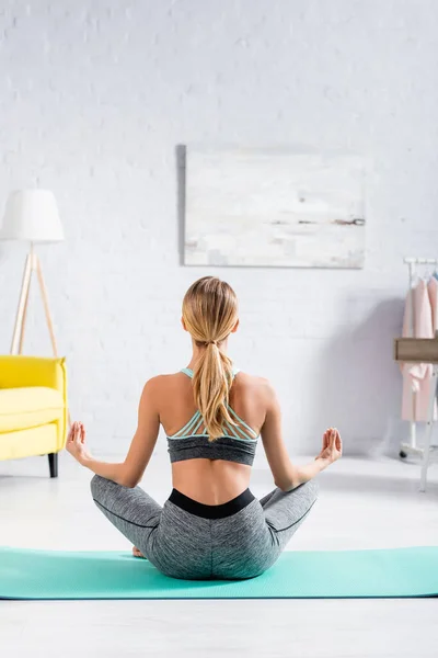 Back view of sportswoman meditating on floor in living room — Stock Photo