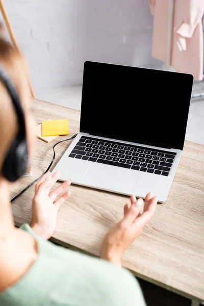 Laptop auf Tisch neben Freelancer im Headset auf verschwommenem Vordergrund zu Hause — Stockfoto