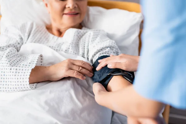 Vista ritagliata del bracciale di fissaggio dell'infermiera del tonometro sul braccio della donna anziana, messa a fuoco selettiva — Foto stock