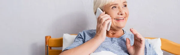 Fröhliche alte Frau telefoniert in Klinik mit Handy, Transparent — Stockfoto