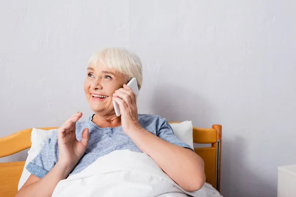 Mulher idosa feliz falando no smartphone no hospital — Fotografia de Stock