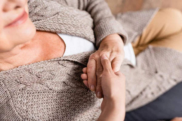 Draufsicht der Seniorin, die die Hand einer Krankenschwester berührt, verschwommener Vordergrund — Stockfoto