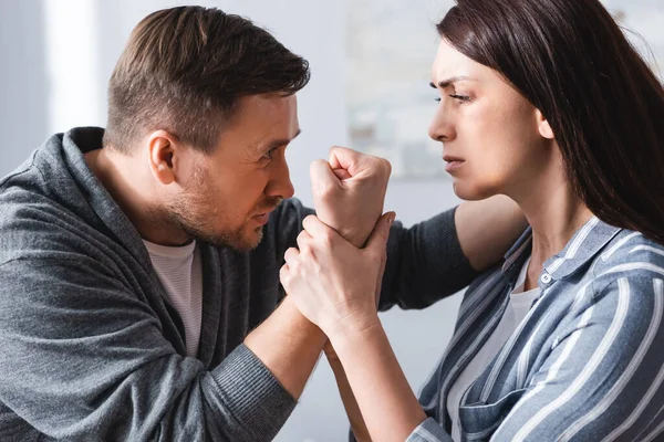 Homem abusivo mostrando punho à esposa com hematomas em casa — Fotografia de Stock