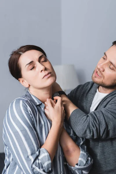 Offended woman with bruise standing near abusive husband at home — Stock Photo