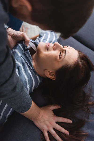 Husband holding shirt of scared wife with bruises near couch — Stock Photo