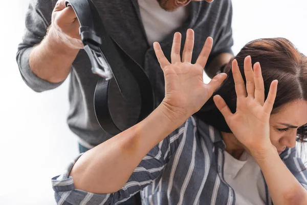 Aggressive husband holding waist belt near frightened wife with bruises on hands — Stock Photo