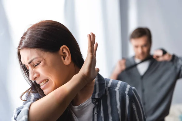 Depressed woman with bruises showing stop near abuser with waist belt on blurred background — Stock Photo