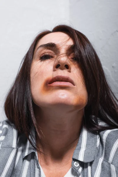 Frau mit blauen Flecken im Gesicht blickt zu Hause in Kamera — Stockfoto