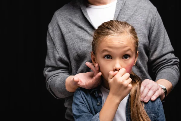 Missbrauch Vater umarmt und berührt verängstigtes Kind mit blauen Flecken isoliert auf schwarz — Stockfoto
