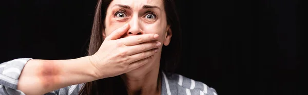 Vítima de abuso doméstico cobrindo boca isolada em preto, banner — Fotografia de Stock