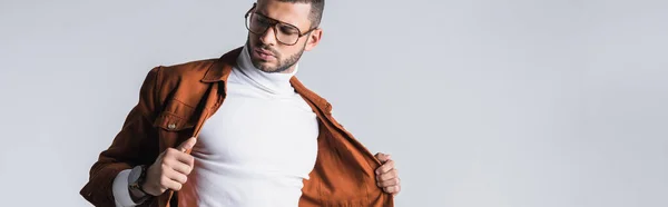 El hombre de moda que sostiene la chaqueta de terracota aislada en gris, bandera - foto de stock