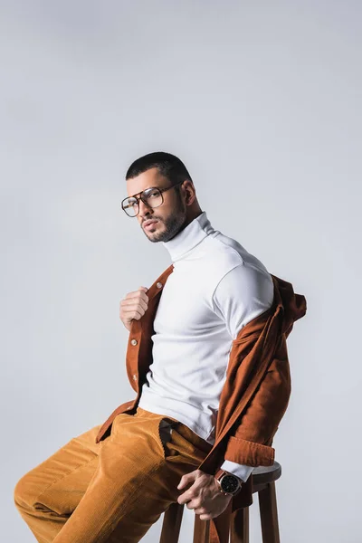 Fashionable man looking at camera while wearing jacket isolated on grey — Stock Photo