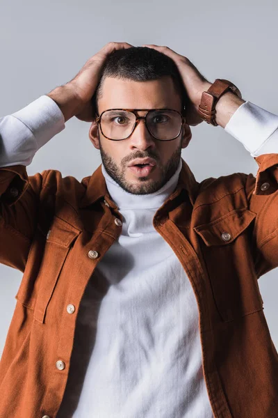 Emocionado hombre con estilo en gafas mirando a la cámara aislada en gris - foto de stock