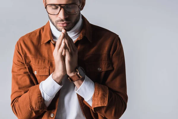 Homme élégant avec les yeux fermés montrant les mains priantes isolées sur gris — Photo de stock