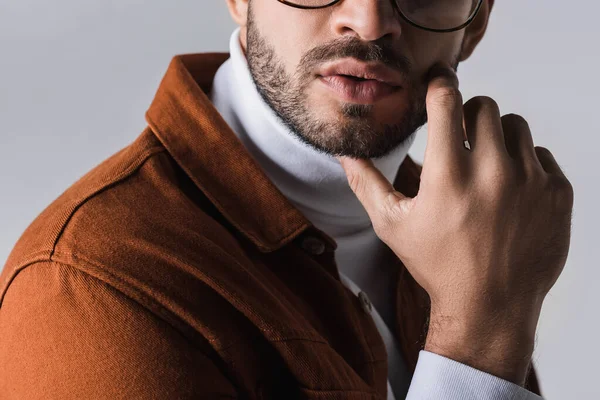 Vista recortada de hombre barbudo con estilo con la mano cerca de la mejilla aislado en gris - foto de stock