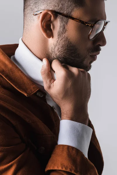 Young man in eyeglasses adjusting collar of white turtleneck isolated on grey — Stock Photo