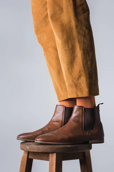 Обрізаний вид на ноги стильного чоловіка в коричневому взутті на стільці ізольовано на сірому — стокове фото