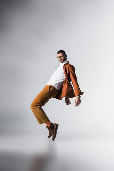 Homem elegante em óculos e roupas casuais posando em fundo cinza — Fotografia de Stock