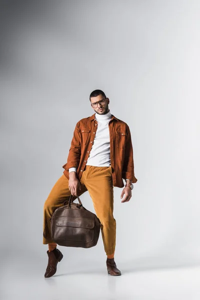 Bearded man with stylish bag looking at camera while posing on grey background — Stock Photo