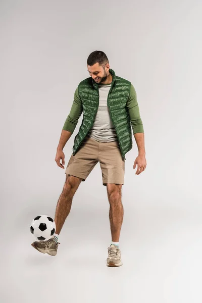 Esportista sorrindo jogando futebol em fundo cinza — Fotografia de Stock