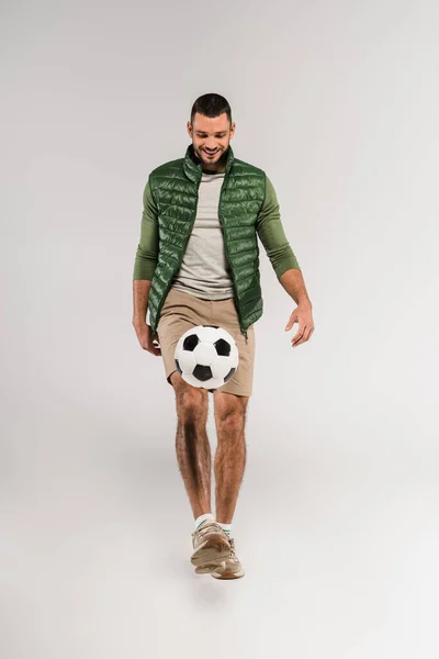 Веселый спортсмен играет в футбол на сером фоне — стоковое фото