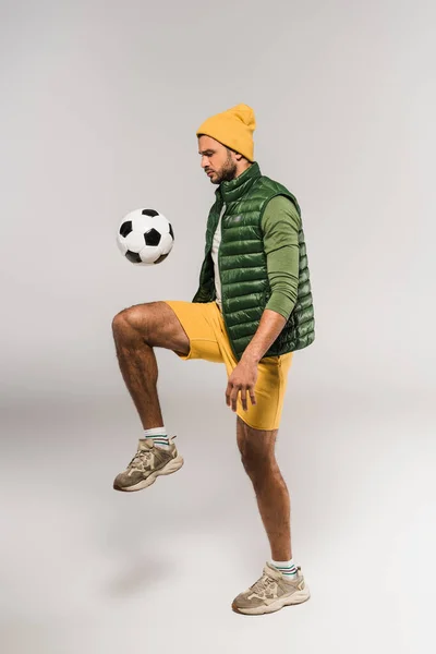 Jovem desportista jogar futebol no fundo cinza — Fotografia de Stock