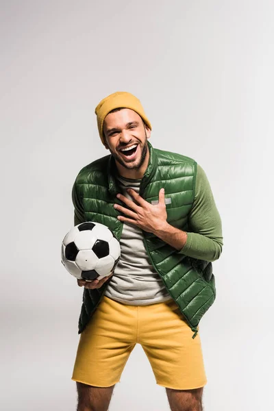 Esportista alegre segurando futebol e olhando para a câmera em fundo cinza — Fotografia de Stock