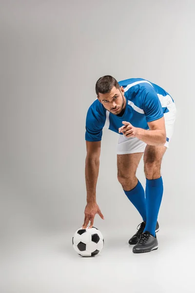 Sportif barbu pointant du doigt la caméra près du football sur fond gris — Photo de stock