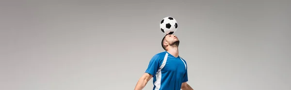 Junger Sportler hält Fußball auf dem Kopf isoliert auf grauem Banner — Stockfoto