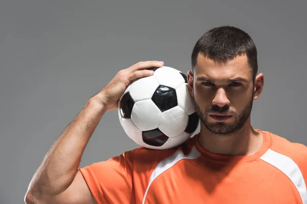 Esportista barbudo segurando futebol perto da cabeça e olhando para a câmera isolada no cinza — Fotografia de Stock