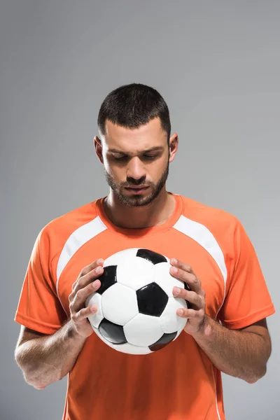 Brunette sportsman looking at football in hands isolated on grey — Stock Photo