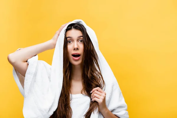 Шокована красива жінка з мокрим волоссям і рушником ізольована на жовтому — стокове фото
