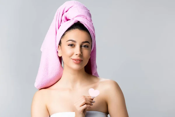 Beautiful woman with towel on hair holding heart shaped sponge isolated on grey — Stock Photo