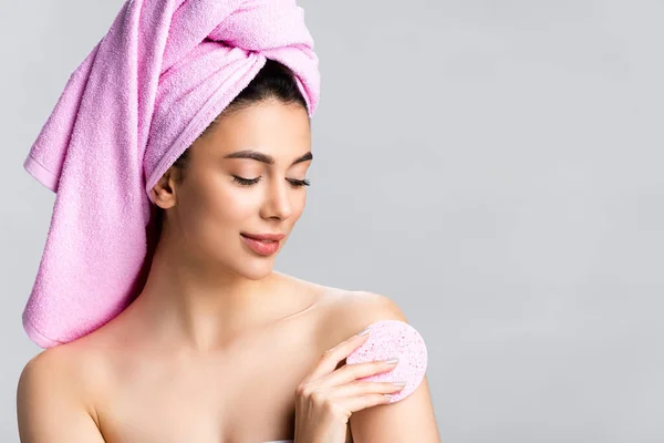 Bela mulher com toalha no cabelo usando esponja isolada no cinza — Fotografia de Stock