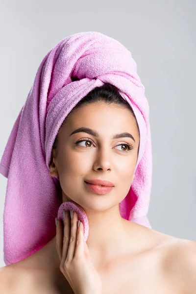 Красивая женщина с полотенцем на волосах с помощью губки изолированы на сером — стоковое фото