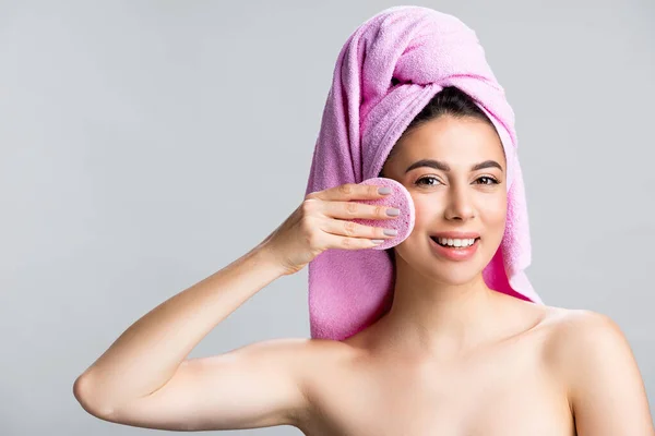 Smiling beautiful woman with towel on hair using sponge isolated on grey — Stock Photo