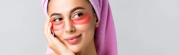 Beautiful woman with towel on hair and hydrogel eye patches on face isolated on grey, banner — Stock Photo