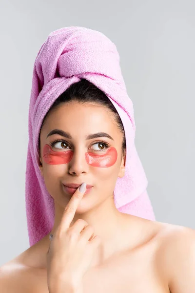 Dreamy beautiful woman with towel on hair and hydrogel eye patches on face isolated on grey — Stock Photo