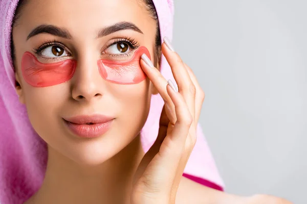 Hermosa mujer con toalla en el cabello y parches de hidrogel en la cara aislado en gris - foto de stock