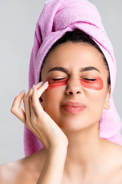 Belle femme avec une serviette sur les cheveux et des patchs hydrogel sur les yeux de fermeture du visage isolés sur gris — Photo de stock
