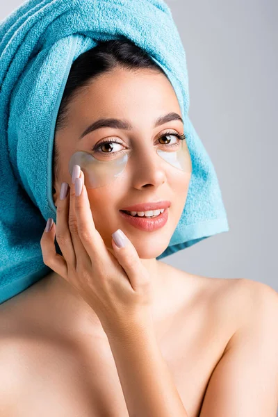 Hermosa mujer sonriente con toalla azul en el cabello y parches de hidrogel en la cara aislada en gris - foto de stock