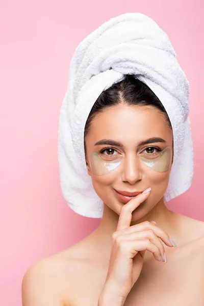 Hermosa mujer sonriente con toalla en el cabello y parches de hidrogel en la cara aislado en rosa - foto de stock