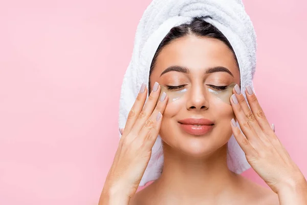 Sonriente hermosa mujer con los ojos cerrados y parches de hidrogel en la cara aislado en rosa - foto de stock